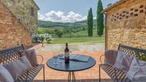 An outdoor patio with a round table, two chairs, and a bottle of wine. - Podere Pisinano- Tuscan villa with swimming pool (Toscana)
