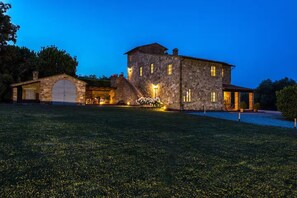 A large stone building with multiple windows and a garage, surrounded by a well-maintained lawn.