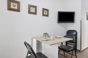 Ein Essbereich mit Tisch, Stühlen, einem Fernseher und gerahmten Bildern an der Wand.