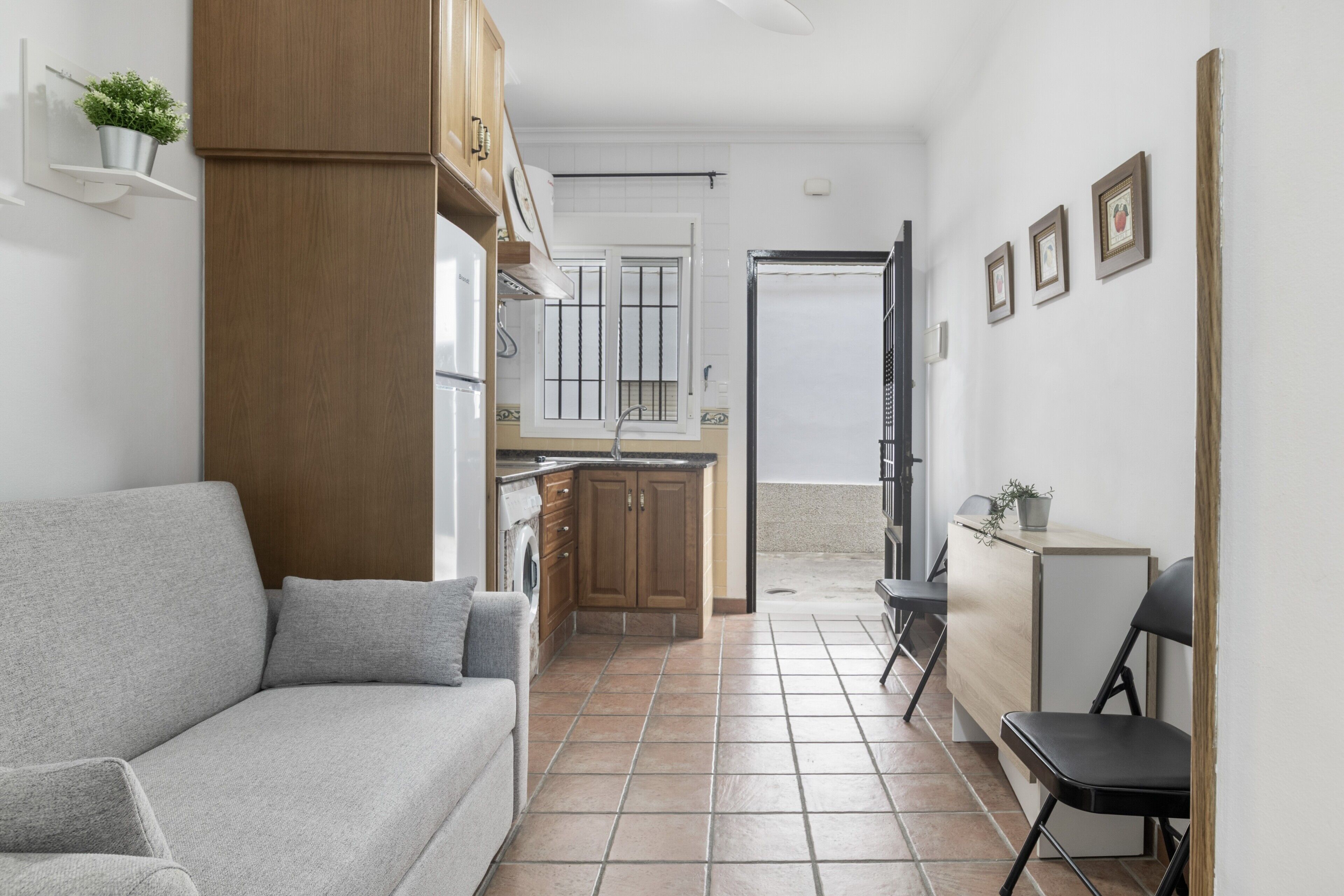 A compact living space with a sofa, kitchenette, and a small dining area.