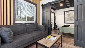 Ein modernes Interieur mit einer Couch, einem Holztisch und einem Bett mit grüner Bettdecke.