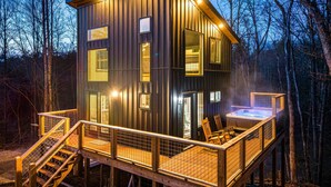 Eine Holzhütte mit einer Terrasse, einem Whirlpool und einer Treppe, die zur Terrasse führt.