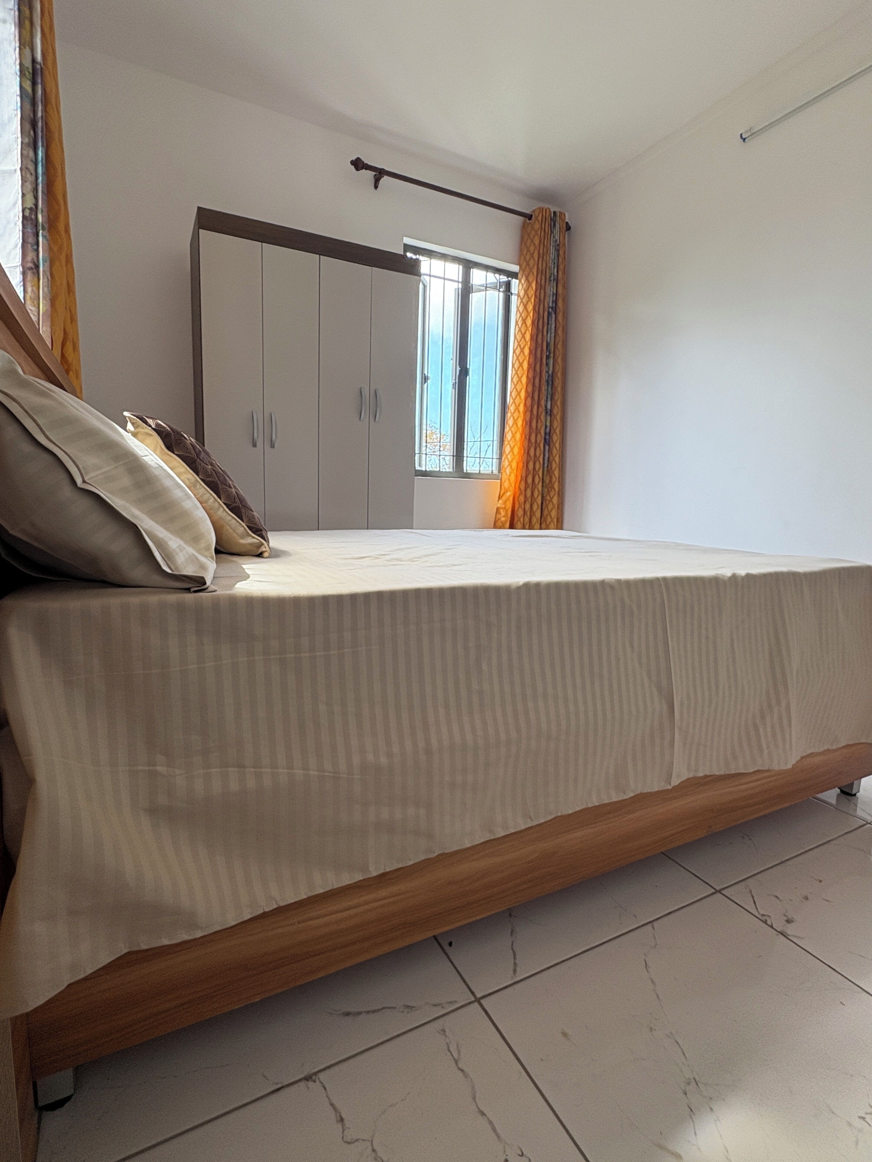Un dormitorio con cama, armario y ventana con cortinas.
