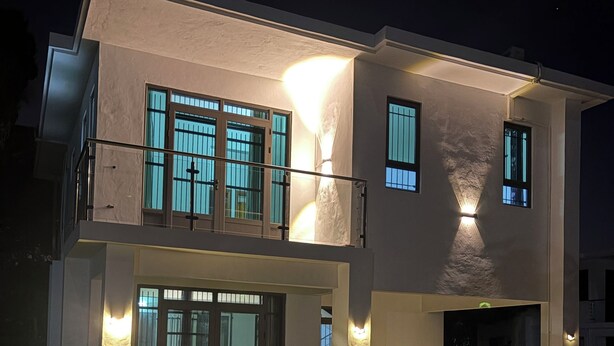 Een modern huis met twee verdiepingen, een overdekte patio en een pad naar de ingang.