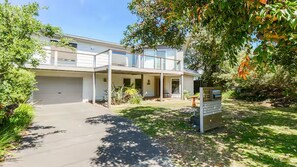 Ein modernes, zweistöckiges Haus mit überdachter Terrasse, Garage und gepflegtem Garten.