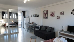 Ein modernes Hotelzimmer mit einer Couch, einem Essbereich und Kunstwerken an den Wänden.
