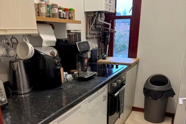A kitchen with a coffee machine, a dishwasher, and a trash can. - 2 Bed Flat - Sleeps 4 - Parking - Wifi (Glasgow)
