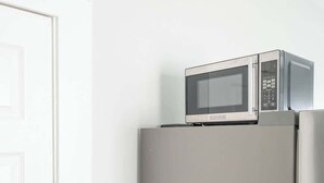 Eine Küche mit einem Edelstahl-Kühlschrank und einer Mikrowelle darauf.