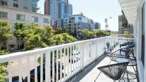 A balcony with a white railing, black chairs, and a small table. - Chic Little Italy Apt | Balcony | Walk Everywhere! (San Diego)