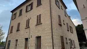 Un bâtiment en pierre à plusieurs étages, doté de nombreuses fenêtres et de volets, et présentant un style architectural traditionnel.