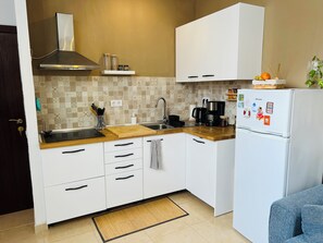 Eine moderne Küche mit weißen Schränken, einer Edelstahl-Dunstesse, einer Kaffeemaschine und einem Kühlschrank mit Magneten.