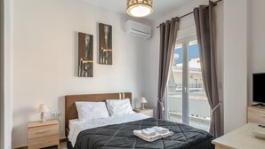 Ein Schlafzimmer mit Bett, Nachttischen, einem Fernseher und einem Fenster mit Vorhängen.