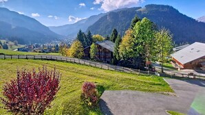 Un paysage montagneux avec un chalet en bois, une zone pavée et un bâtiment doté d’un toit en pente.