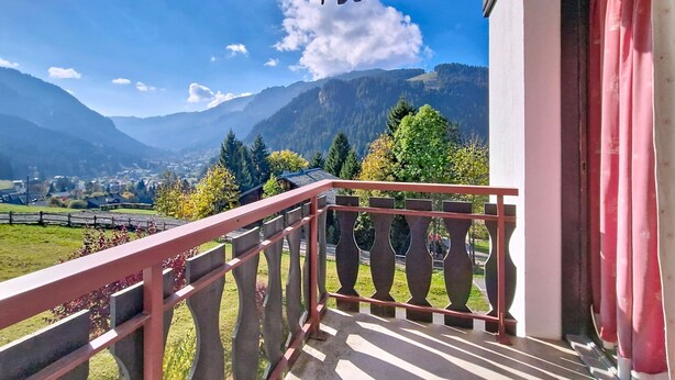 Un balcon offrant une vue sur les montagnes et un village situé en contrebas.
