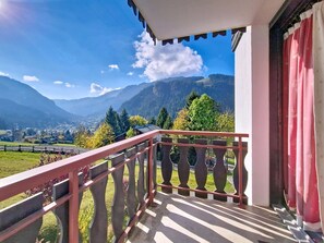 Un balcon offrant une vue sur les montagnes et un village situé en contrebas.