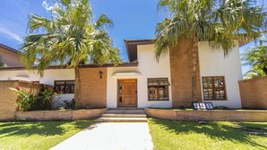 A two-story house with a central entrance, a brick facade, and a well-maintained lawn. - Casa c Piscina e Churrasqueira em Condom nio (Guarujá)
