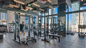 Ein modernes Fitnessstudio mit verschiedenen Gewichtsmaschinen, großen Fenstern und Stadtblick sowie einem großzügigen Raumangebot.