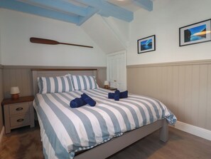 Una camera da letto con un letto, un comodino, un remo di legno e due quadri appesi al muro.