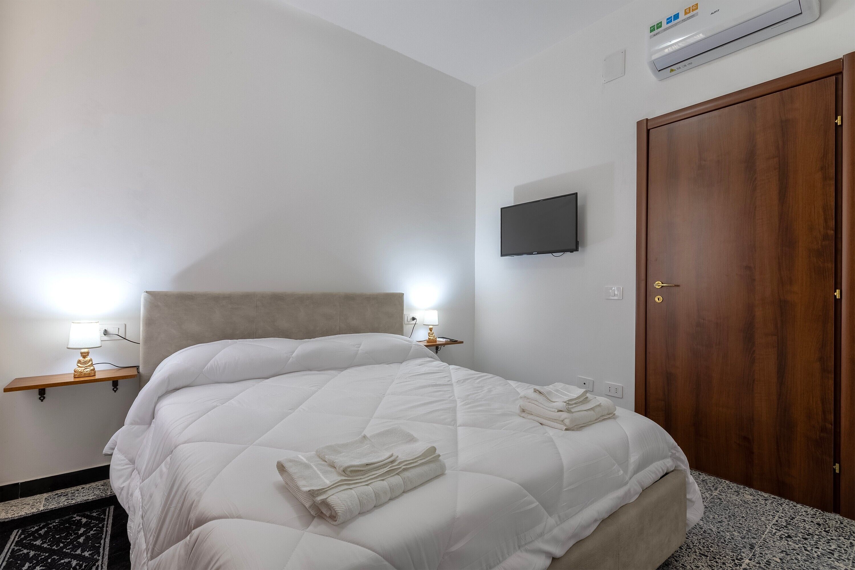 Ett hotellrum med en stor säng, sänglampor, en tv och en dörr av trä.