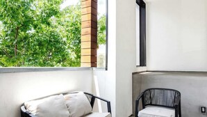Un balcon moderne avec un canapé, une table ronde et deux chaises.