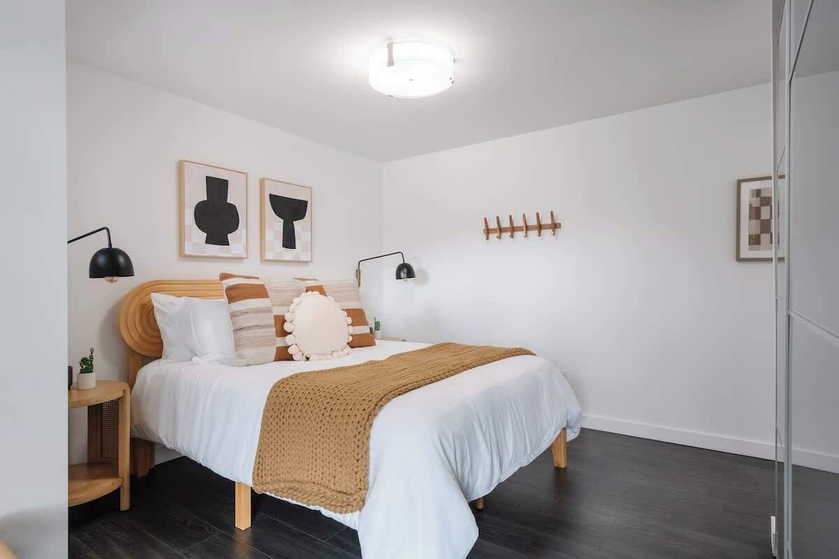 A bedroom with a bed, bedside tables, a lamp, and wall art.