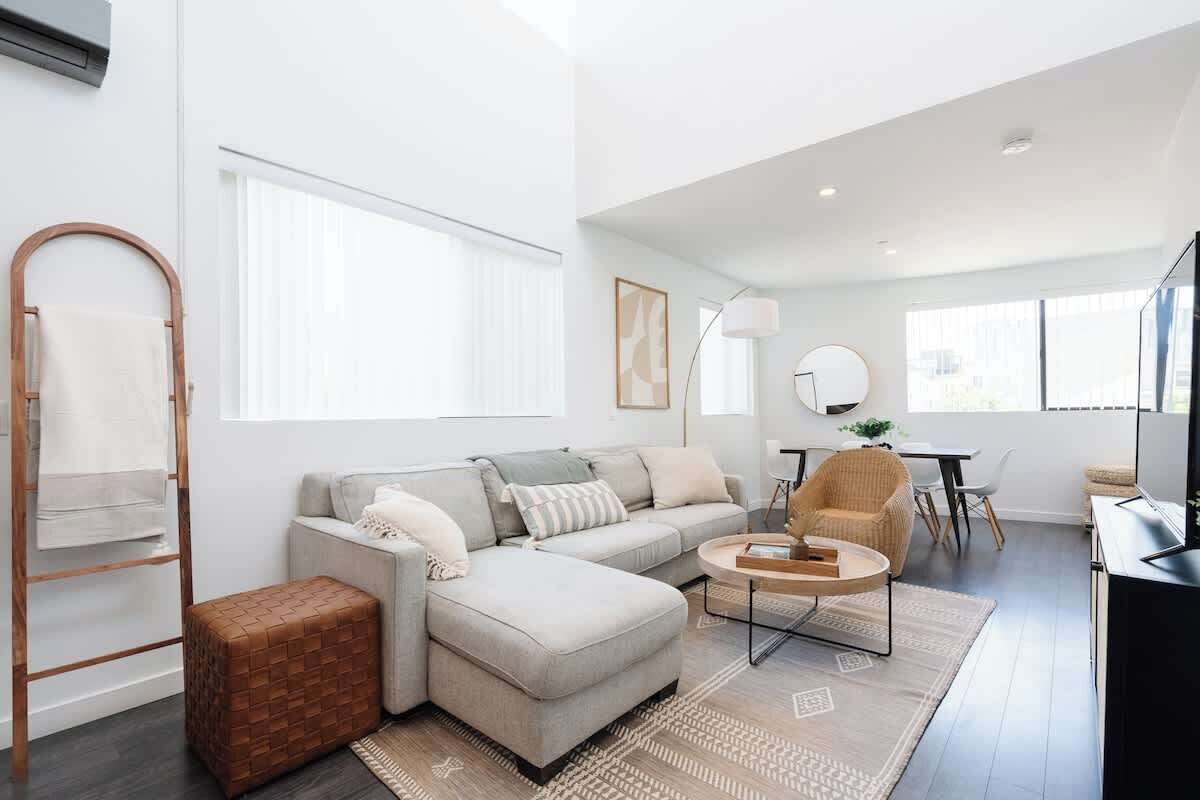 A modern living room with a sectional sofa, a coffee table, and a dining area with a table and chairs.