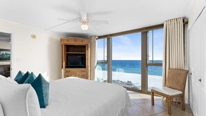 A hotel room with a large bed, a television, a chair, and a view of the ocean. - Perdido Towers West 606 (Pensacola)