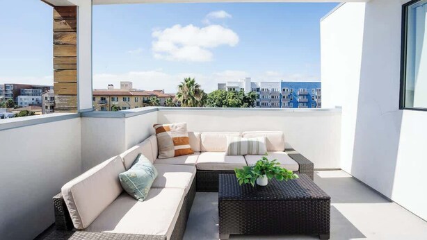 Un balcón con sofá y mesa de centro, con vista a un paisaje urbano.