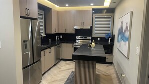 Una cocina moderna con electrodomésticos de acero inoxidable, gabinetes de madera y una encimera negra.