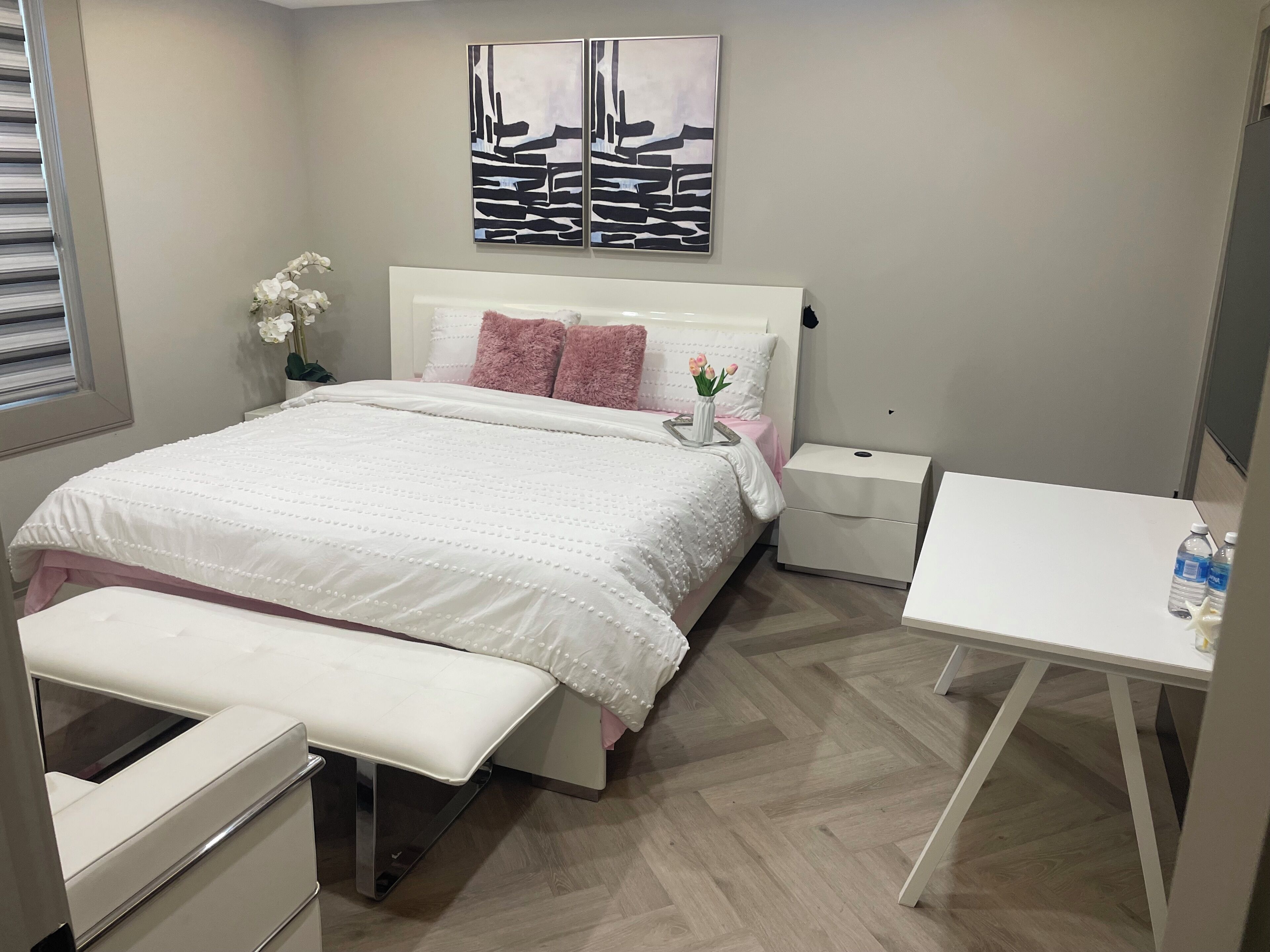 A neatly arranged bedroom with a bed, bedside tables, a bench, and a desk.