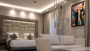 A modern bedroom with a large bed, a sofa, and a painting on the wall. - RV Hotel - Dely Brahim (Algiers)