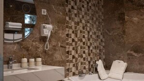 A modern bathroom with a marble wall, a wooden bathtub, a vanity with a mirror, and a towel rack. - RV Hotel - Dely Brahim (Algiers)