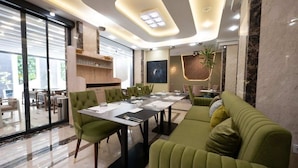 A modern dining area with a long table, green upholstered chairs, and a sofa. - RV Hotel - Dely Brahim (Algiers)