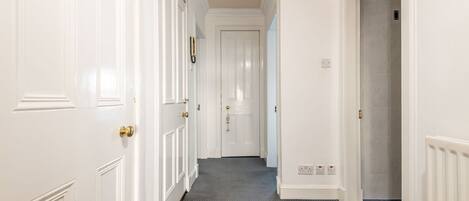 A hallway with white doors, a patterned carpet, and a radiator on the right wall.