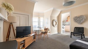 Ein Wohnzimmer mit Fernseher, einer Holzunterhaltungsecke und einem Essbereich mit Tisch und Stühlen.