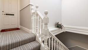 Eine Treppe mit weißen Balustern und einer roten Fußmatte.
