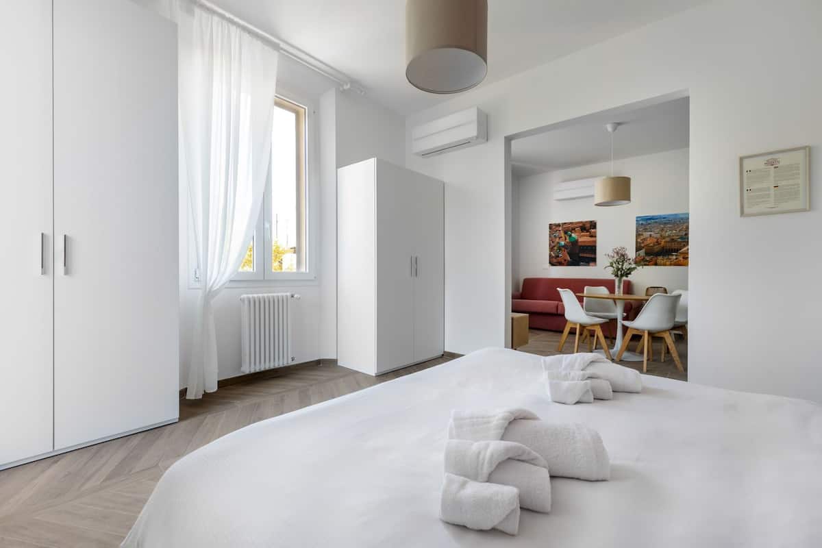 Una habitació d'hotel moderna amb un llit gran, una zona de menjador i vistes a la ciutat.