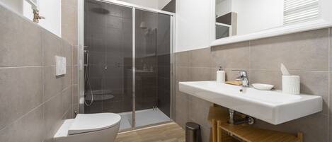 Une salle de bain moderne équipée d’une douche, de toilettes et d’un lavabo.