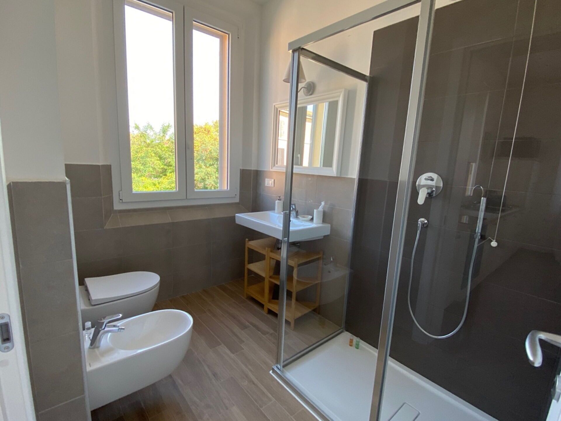 A modern bathroom with a toilet, sink, and glass-enclosed shower.