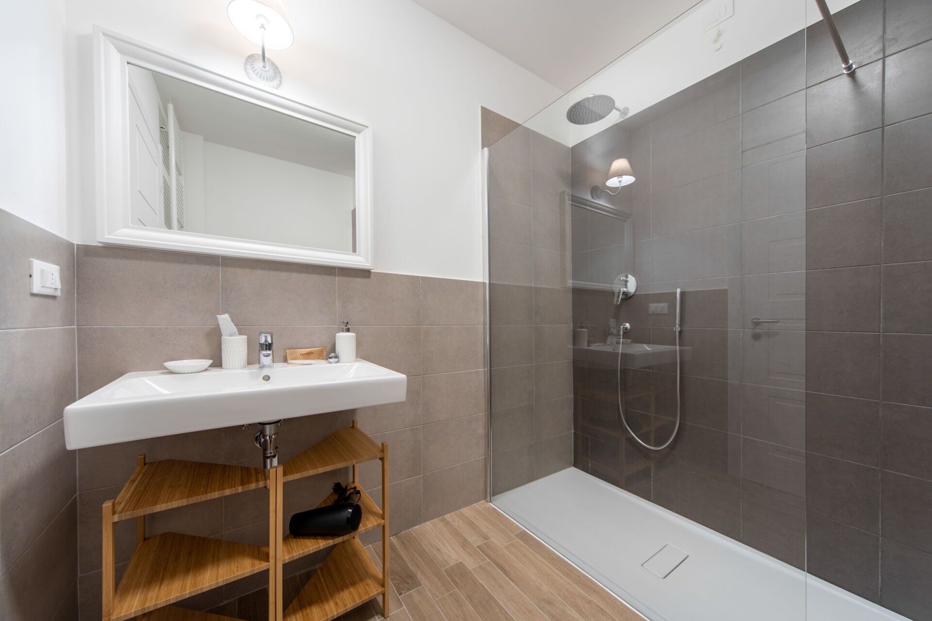 Un baño moderno con lavamanos, espejo y ducha blancos.