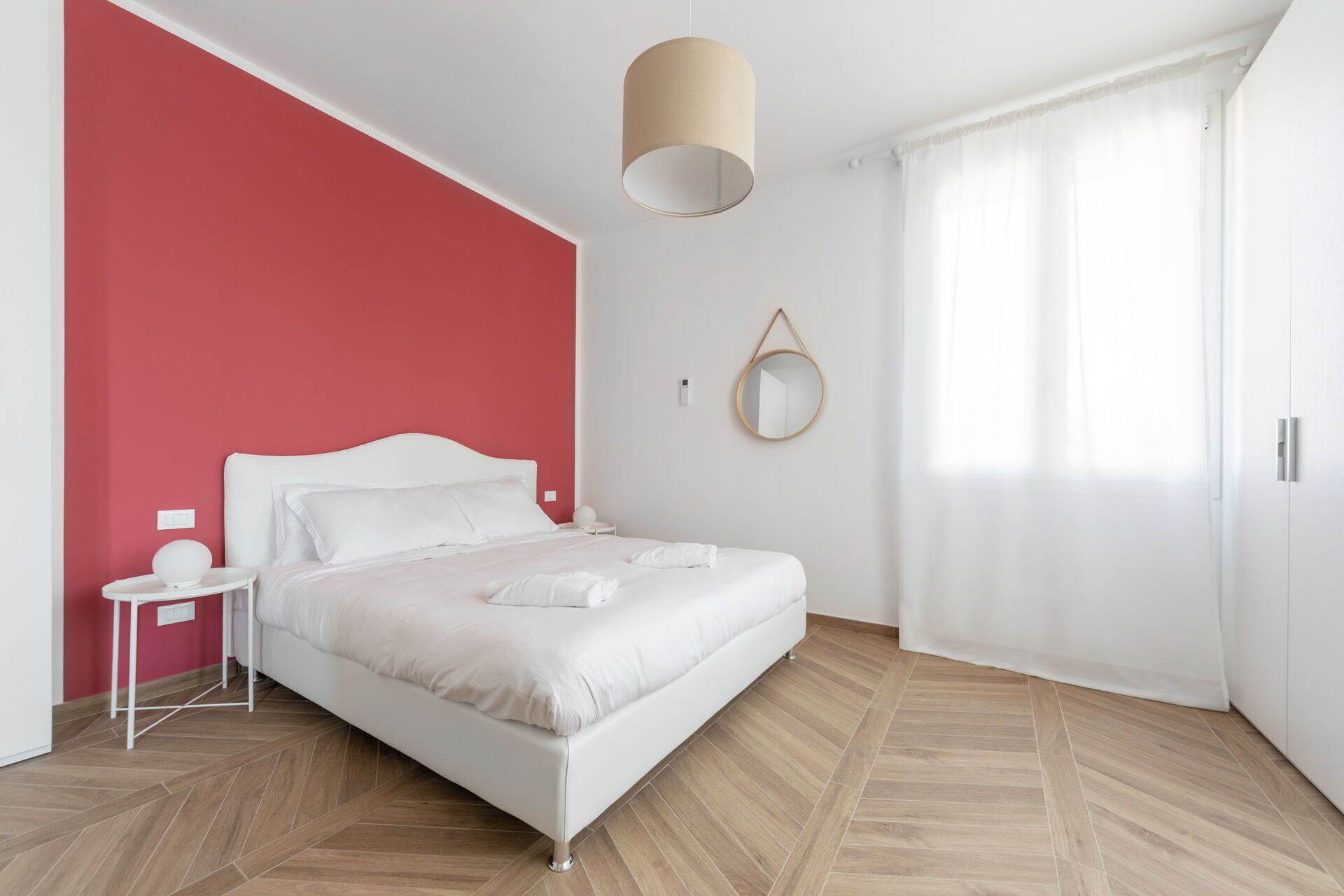 Une chambre à coucher moderne avec un lit, une table de chevet et une lampe suspendue.