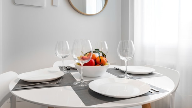 A dining table set with white plates, wine glasses, and a bowl of fruit. - Palazzo Pedretti by Halldis (Bologna)