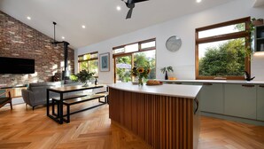 Une cuisine moderne avec un parquet en bois disposé en chevrons, un îlot central intégré et de grandes fenêtres offrant une vue sur la verdure.