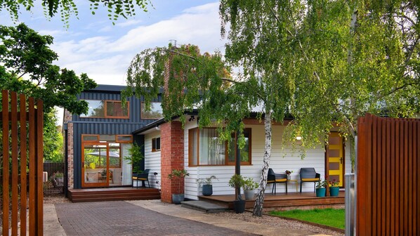 Ein modernes Haus mit Ziegelaußenwand, großen Fenstern und einer Holzterrasse.