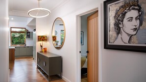 Un couloir avec une cuisine moderne, un grand miroir et une œuvre d’art encadrée accrochée au mur.