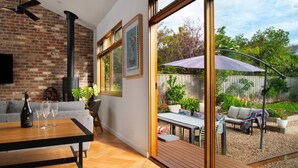 Un salon moderne doté d’une cheminée, d’un coin repas et offrant une vue sur un jardin avec un espace salon extérieur.