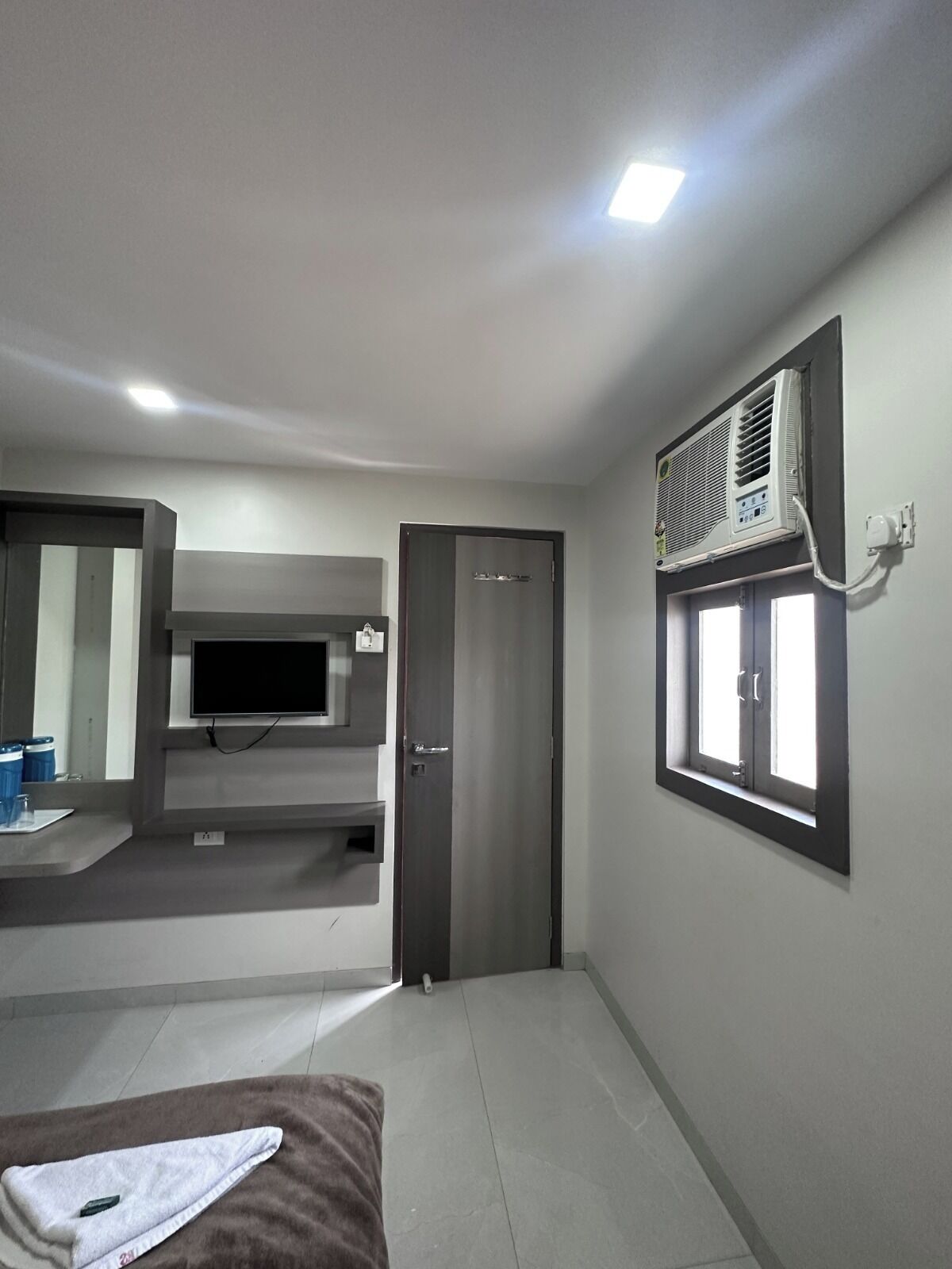 Ein Hotelzimmer mit Fernseher, Klimaanlage und einer Tür zu einem weiteren Raum.