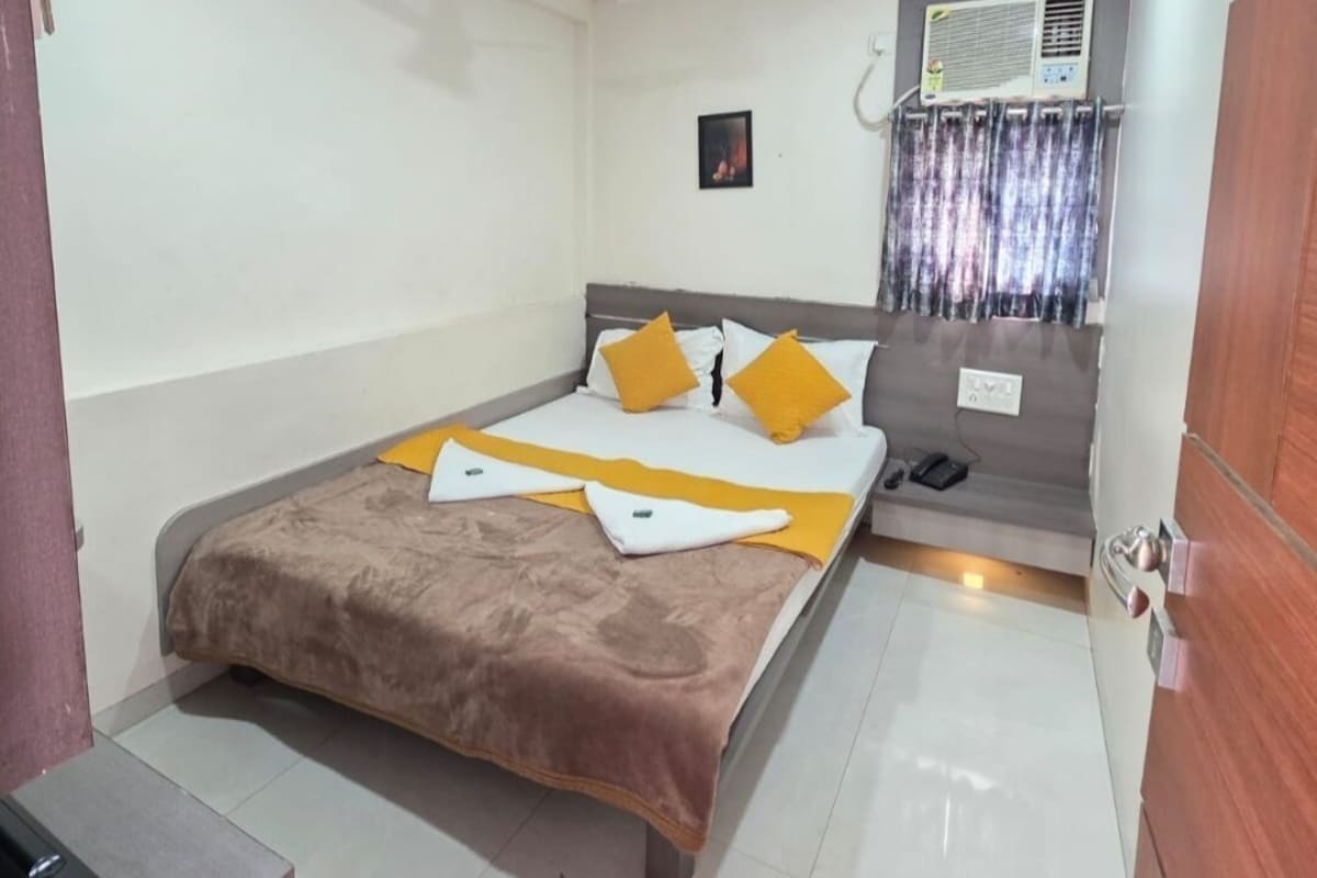 Une chambre d’hôtel équipée d’un lit, d’une table de chevet, d’un climatiseur fixé au mur et d’un ventilateur de plafond.
