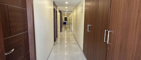 A long, narrow hallway with wooden wardrobes on both sides and a tiled floor.