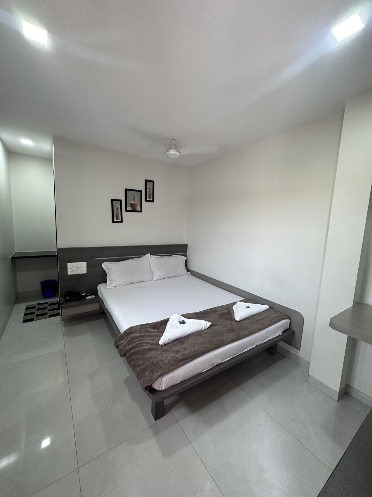Habitación de hotel moderna con una cama individual, una mesita de noche, una pequeña mesa y un ventilador de techo.